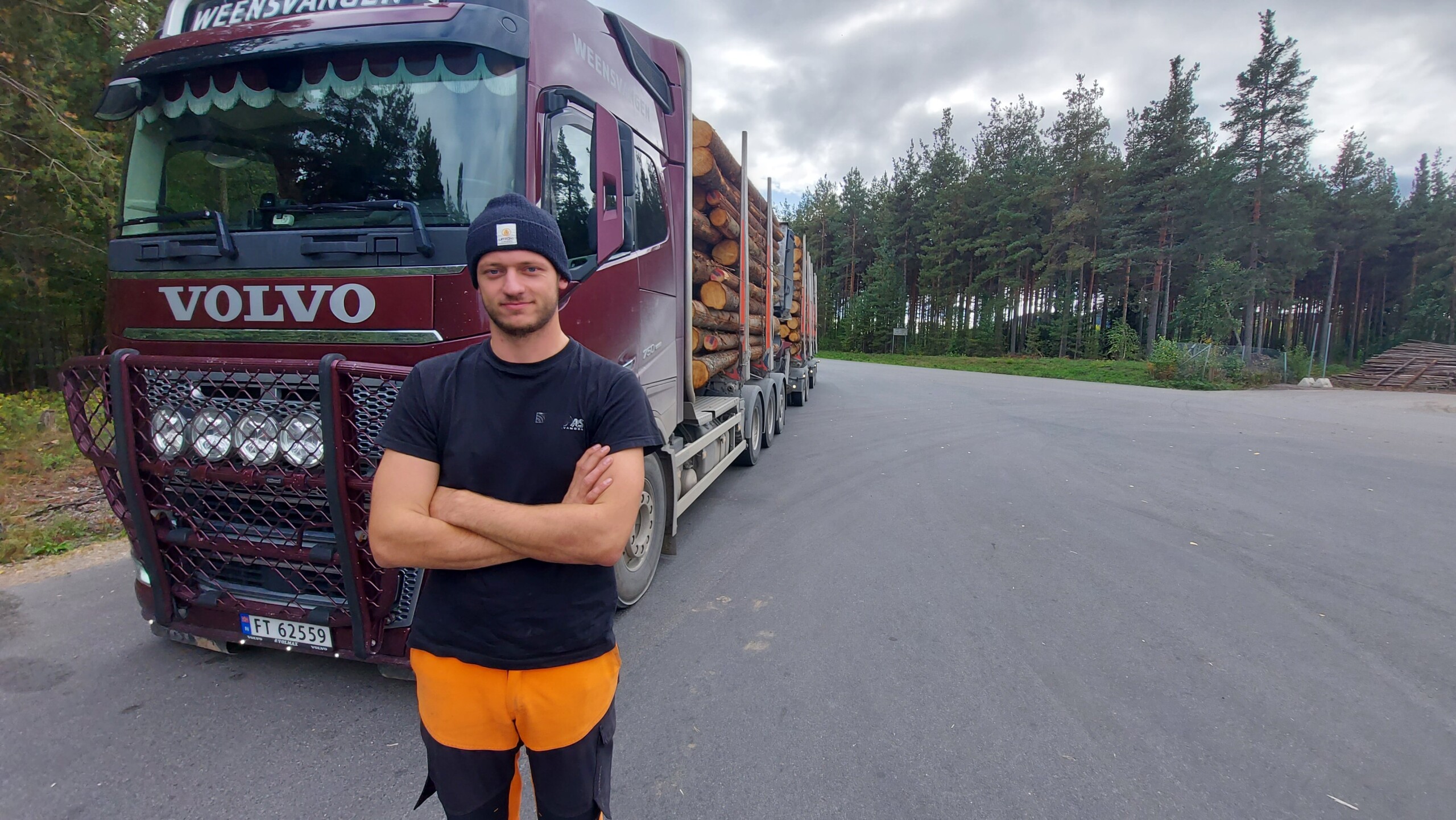 Yrkessjåfør poserer foran tømmerbil